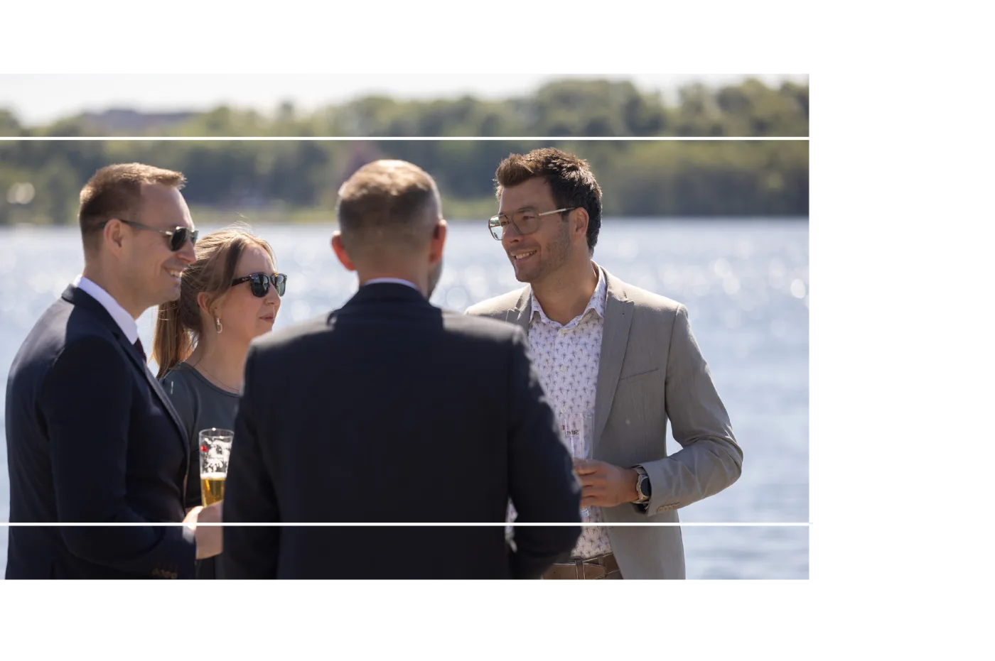 Gäste im Gespräch auf einer Terrasse am Wasser
